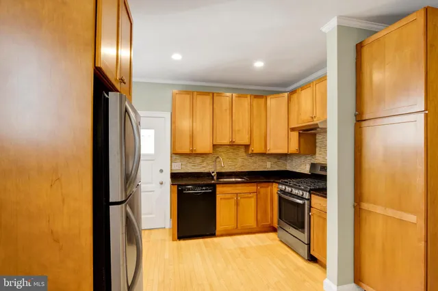 a kitchen with stainless steel appliances granite countertop a refrigerator a stove and a sink