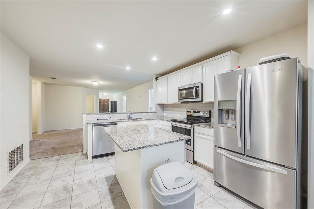 1062 Spofford Drive Forney, TX 75126 - Photo 11 of 23 a kitchen with stainless steel appliances sinks a refrigerator and a stove top oven