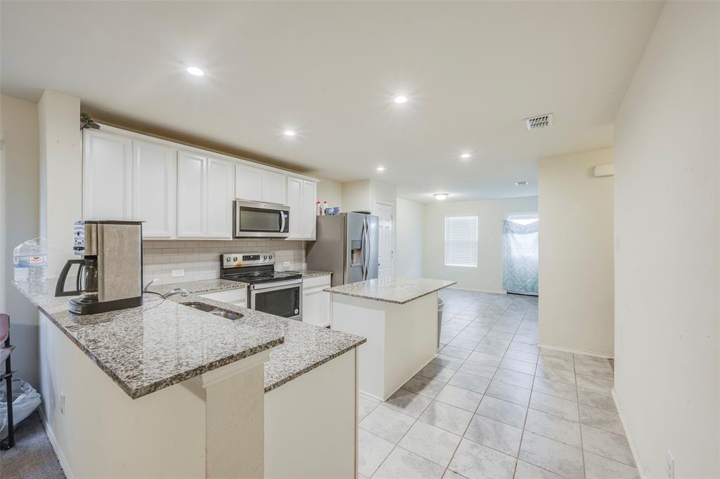 1062 Spofford Drive Forney, TX 75126 - Photo 9 of 23 a kitchen with stainless steel appliances granite countertop a sink stove and refrigerator