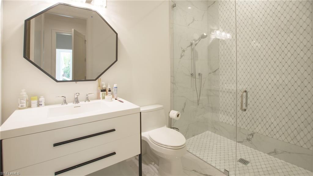 700 Wedge Drive Naples, FL 34103 - Photo 11 of 19 Bathroom featuring a shower with shower door, toilet, and vanity
