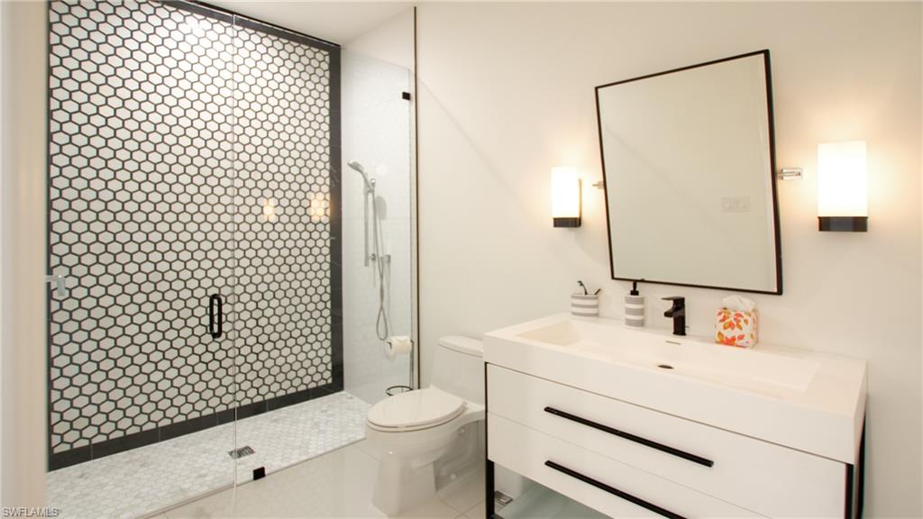 700 Wedge Drive Naples, FL 34103 - Photo 15 of 19 Bathroom with vanity, toilet, and a tile shower