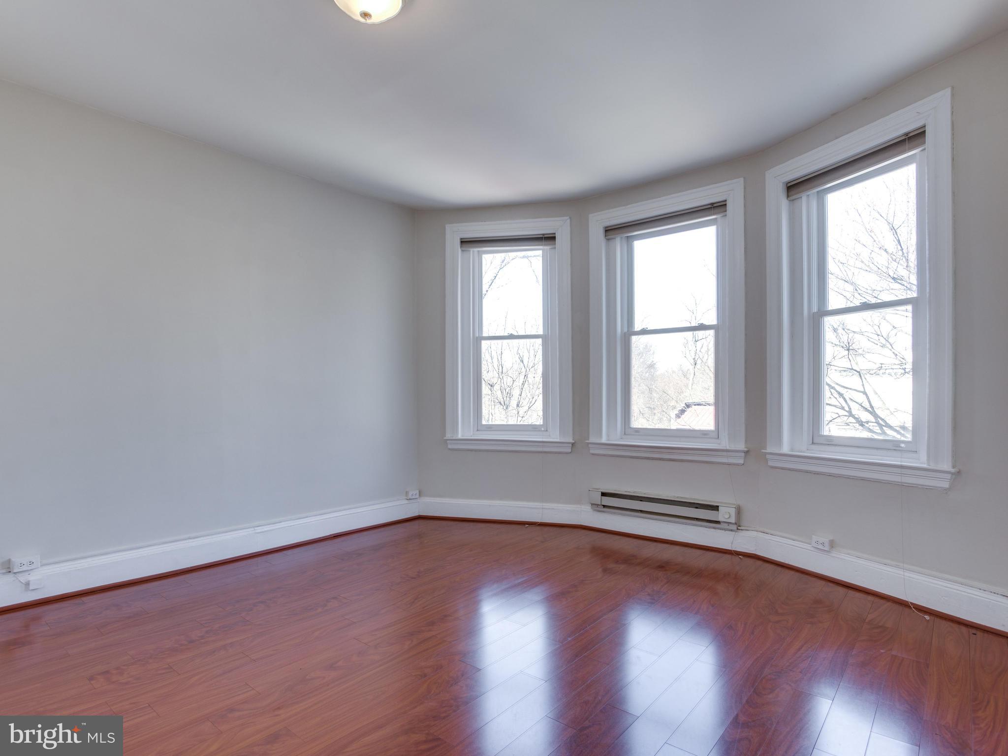 1954 Calvert Street Northwest Washington, DC 20009 - Photo 19 of 28 an empty room with wooden floor and windows