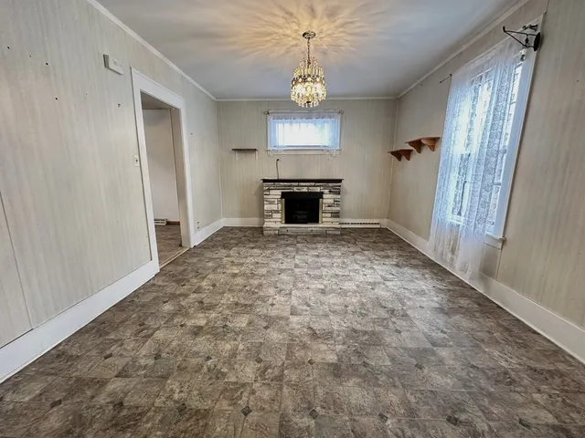 an empty room with windows and fireplace