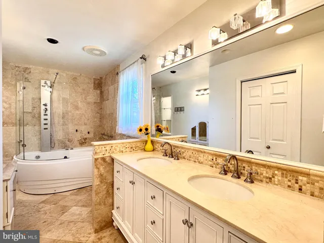 a bathroom with a double vanity sink a mirror and a bathtub