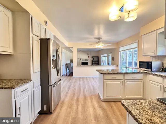 a kitchen with stainless steel appliances granite countertop a refrigerator a stove a sink dishwasher and a stove with wooden floor