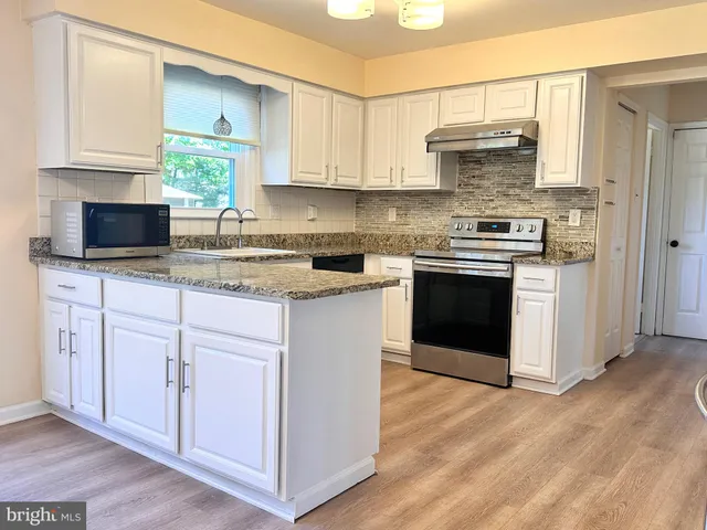 a kitchen with stainless steel appliances granite countertop a stove a sink and a microwave