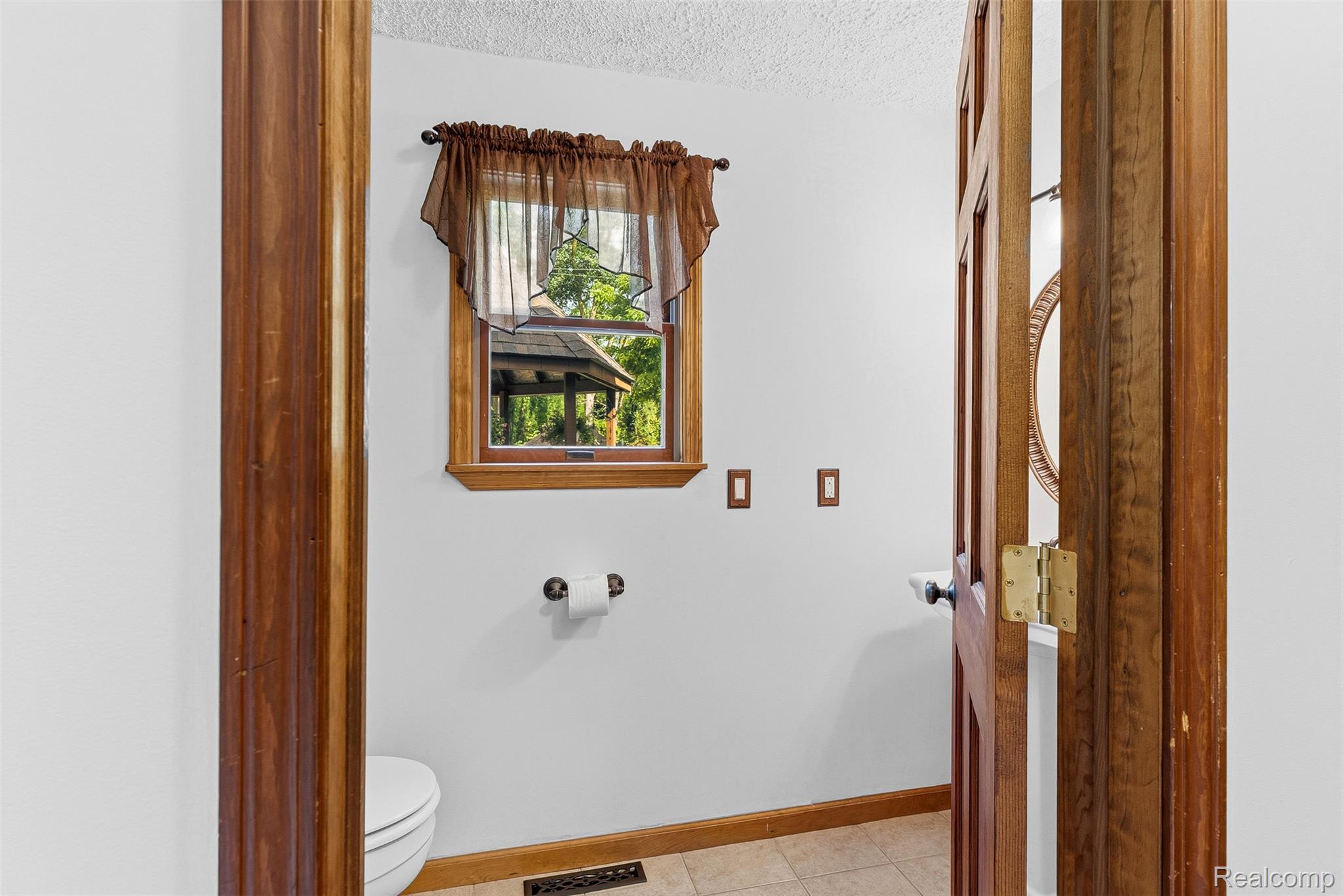 6699 Lansing Road Durand, MI 48429 - Photo 24 of 53 Bathroom featuring a window with exterior garden structure, wood-trim window frame, tile flooring, and wood door frame