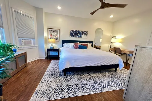 a bedroom with a large bed a rug and potted plant
