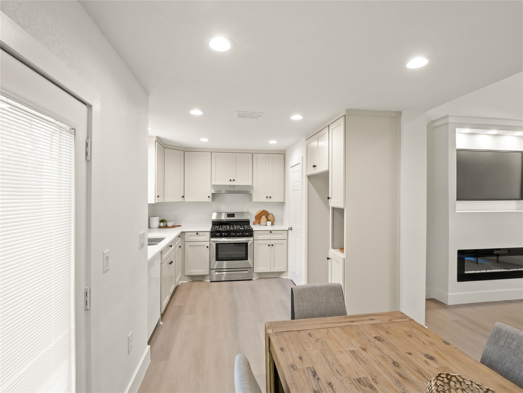 218 Crystal Knoll Boulevard Georgetown, TX 78626 - Photo 9 of 27 Kitchen featuring gas stove, white cabinets, light wood-style flooring, recessed lighting, and a glass covered fireplace