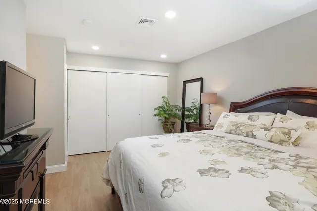 a bedroom with a bed and a flat tv screen on dresser