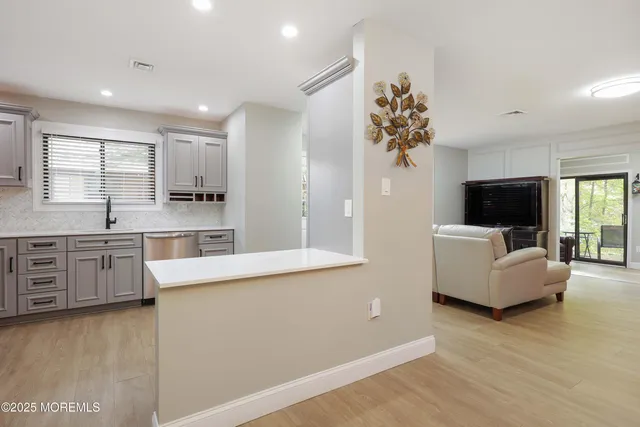 a living room with stainless steel appliances kitchen island granite countertop a couch and a flat screen tv