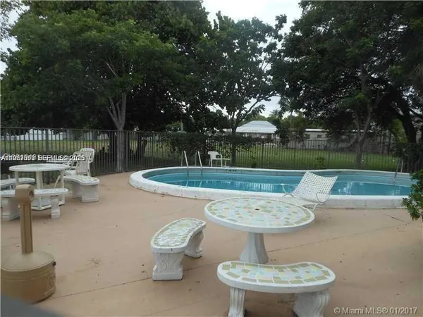 a view of a patio with table and chairs potted plants and floor to ceiling window