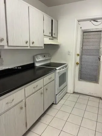 a kitchen with a refrigerator and white cabinets