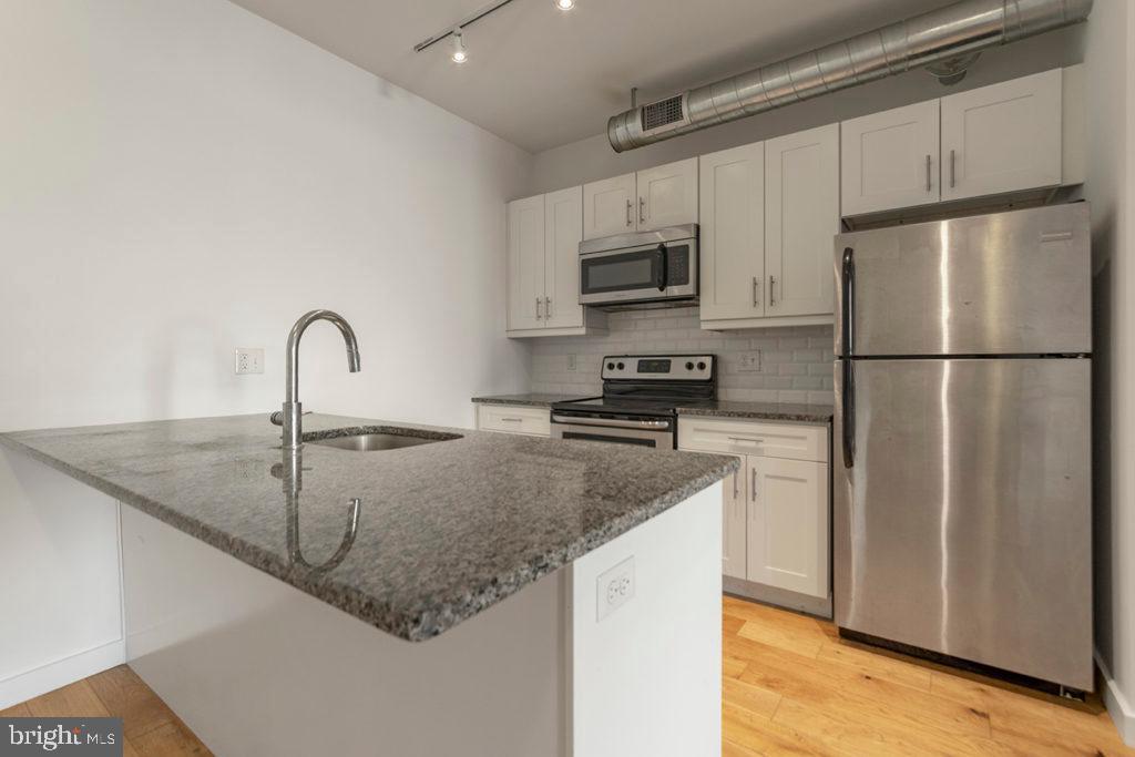 224 Church Street, Unit 406 Philadelphia, PA 19106 - Photo 3 of 14 a kitchen with stainless steel appliances granite countertop a sink a refrigerator a stove a microwave and cabinets