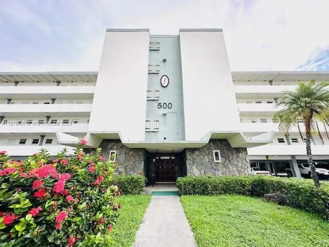 a front view of a multi story residential apartment building with yard and parking area