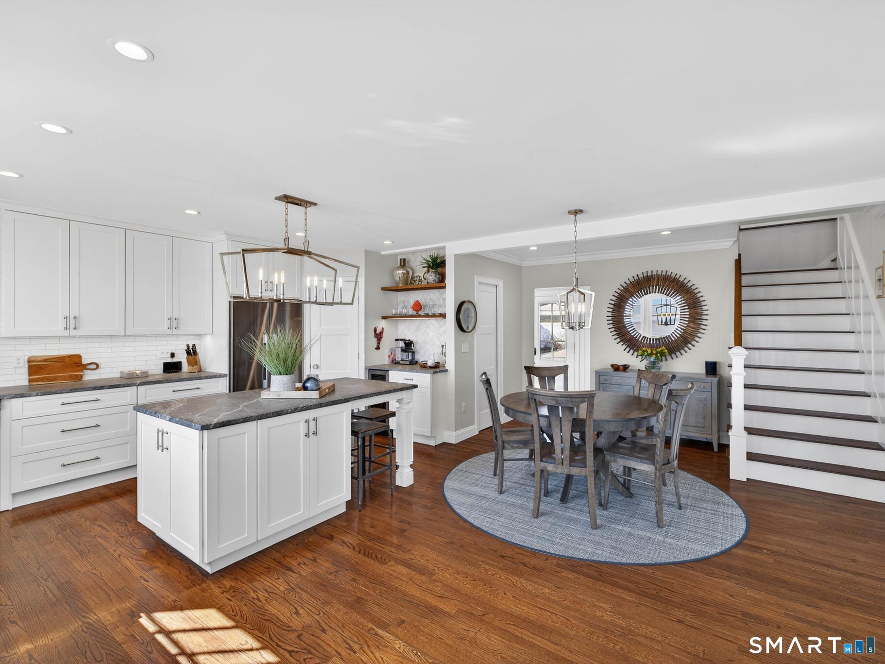 382 Maple Avenue Old Saybrook, CT 06475 - Photo 17 of 42 a kitchen with stainless steel appliances granite countertop a stove top oven a sink a dining table and chairs with wooden floor