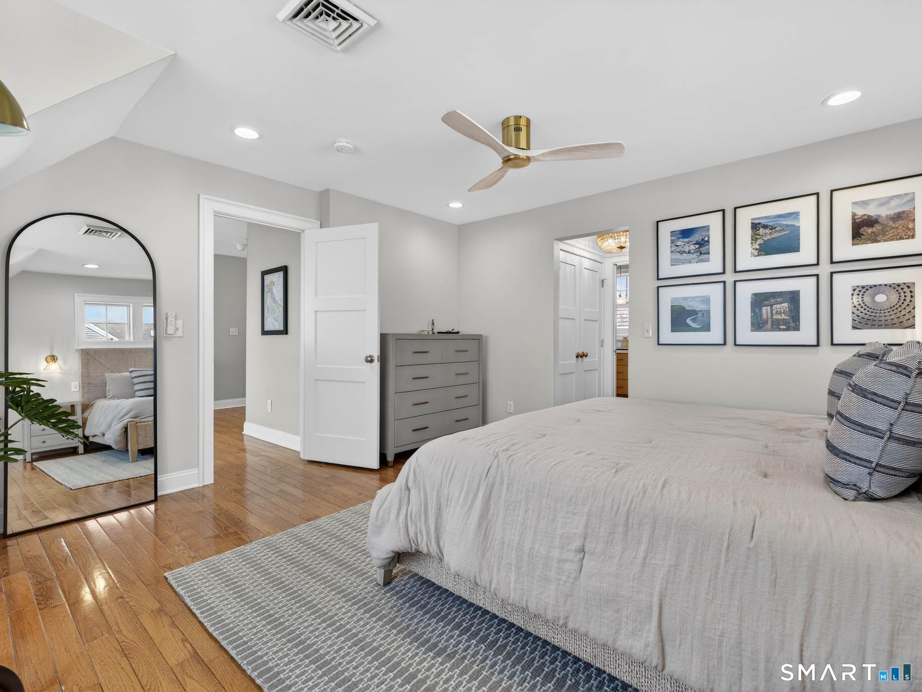 382 Maple Avenue Old Saybrook, CT 06475 - Photo 35 of 42 a spacious bedroom with a bed a mirror and lamp on table