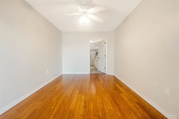 an empty room with wooden floor and fan