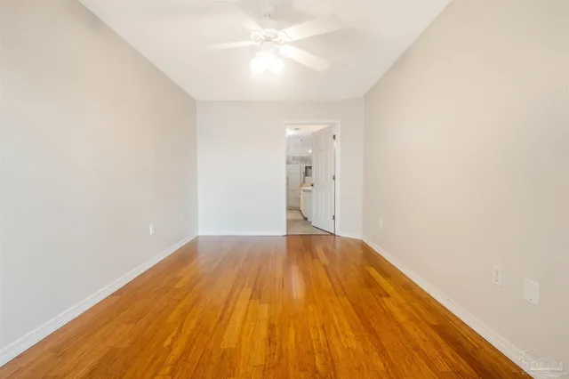 an empty room with wooden floor and fan