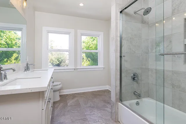 a bathroom with a granite countertop sink a toilet and shower