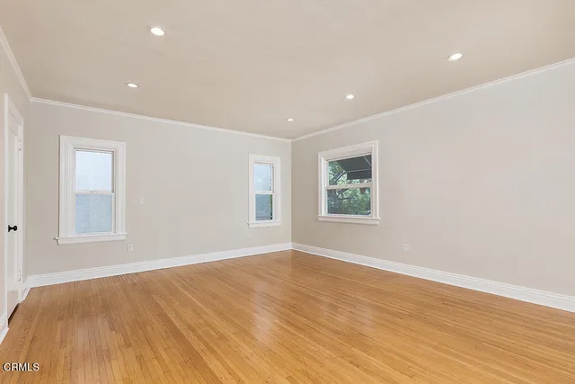 a view of empty room with wooden floor and fan