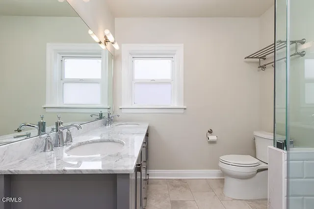 a bathroom with a granite countertop toilet a sink and a mirror