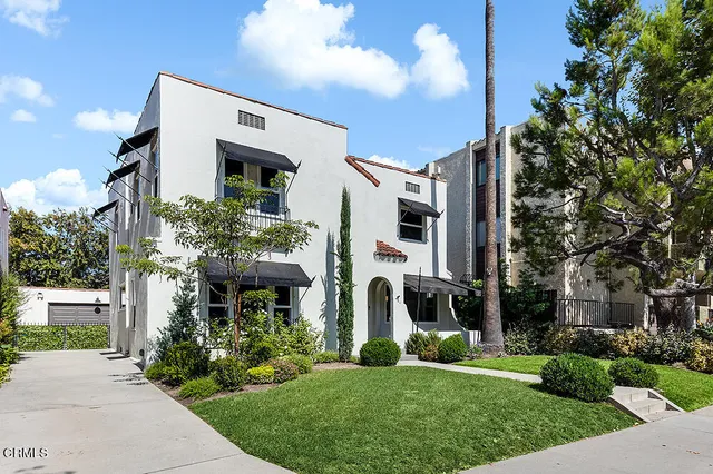a front view of a house with a yard and potted plants
