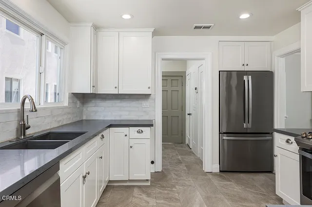 a kitchen with white cabinets and stainless steel appliances