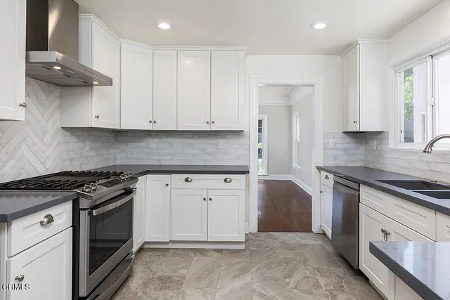 a kitchen with granite countertop white cabinets and stainless steel appliances