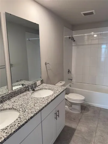 a bathroom with a granite countertop sink a toilet and a mirror
