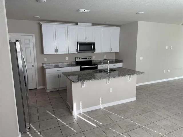 a kitchen with stainless steel appliances granite countertop a refrigerator a stove a sink and a granite counter tops