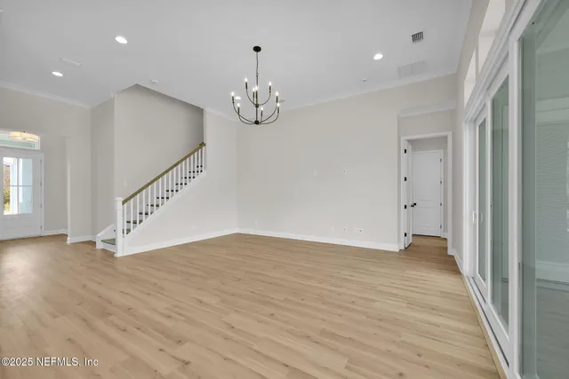 an empty room with wooden floor and staircase