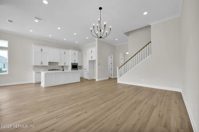 a view of an empty room with kitchen and window