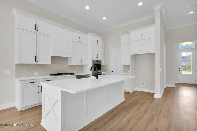 a kitchen with a sink a stove a refrigerator and white cabinets with wooden floor