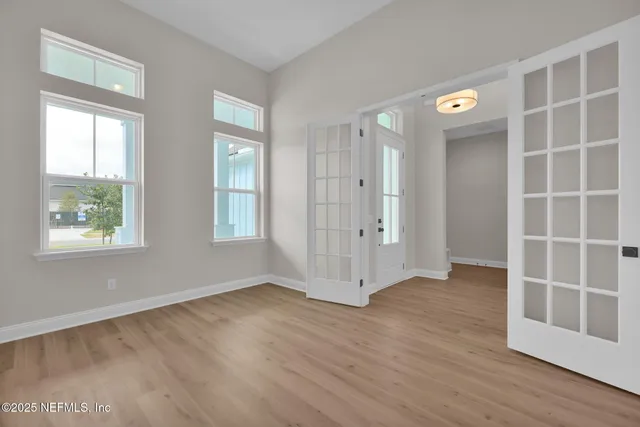 an empty room with wooden floor and windows