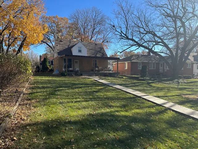 a big yard with large trees and a wooden fence