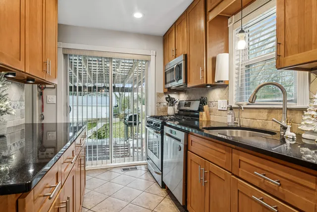 a kitchen with stainless steel appliances granite countertop a sink a stove and a wooden cabinets