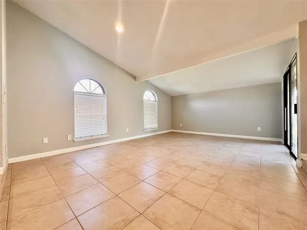 a view of an empty room with window and chandelier