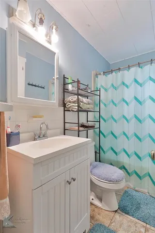 a bathroom with a sink a toilet a mirror and shower curtain