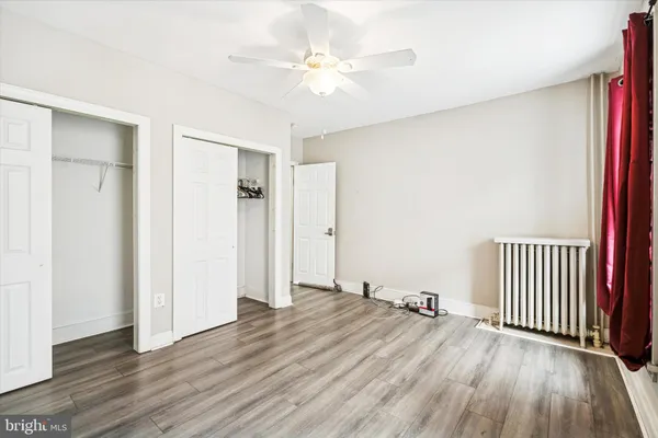 an empty room with wooden floor and a ceiling fan