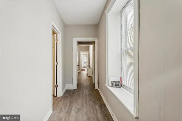 a view of a hallway with wooden floor and a bathroom