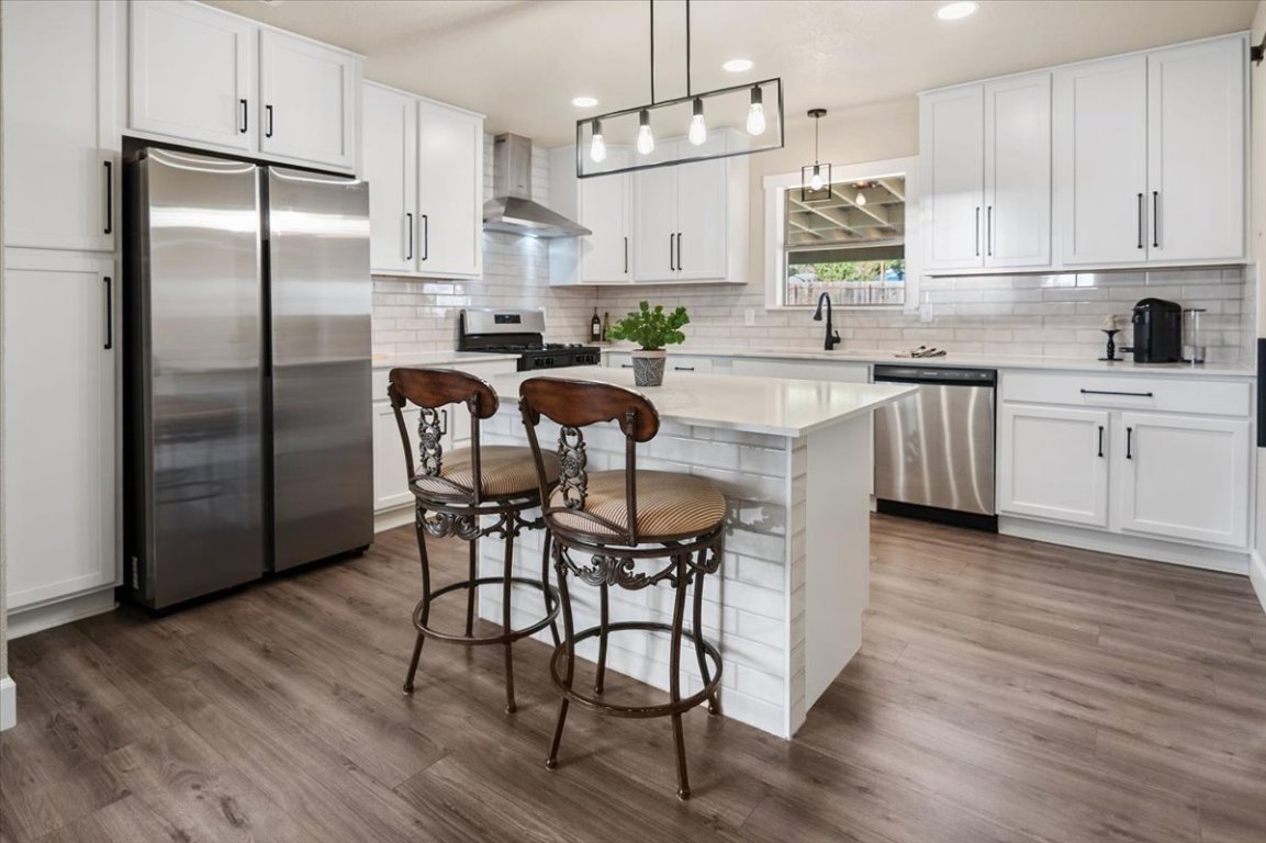 1236 Martin Street Mason, TX 76856 - Photo 8 of 40 a kitchen with stainless steel appliances granite countertop a white refrigerator a sink a stove a dining table and chairs with wooden floor