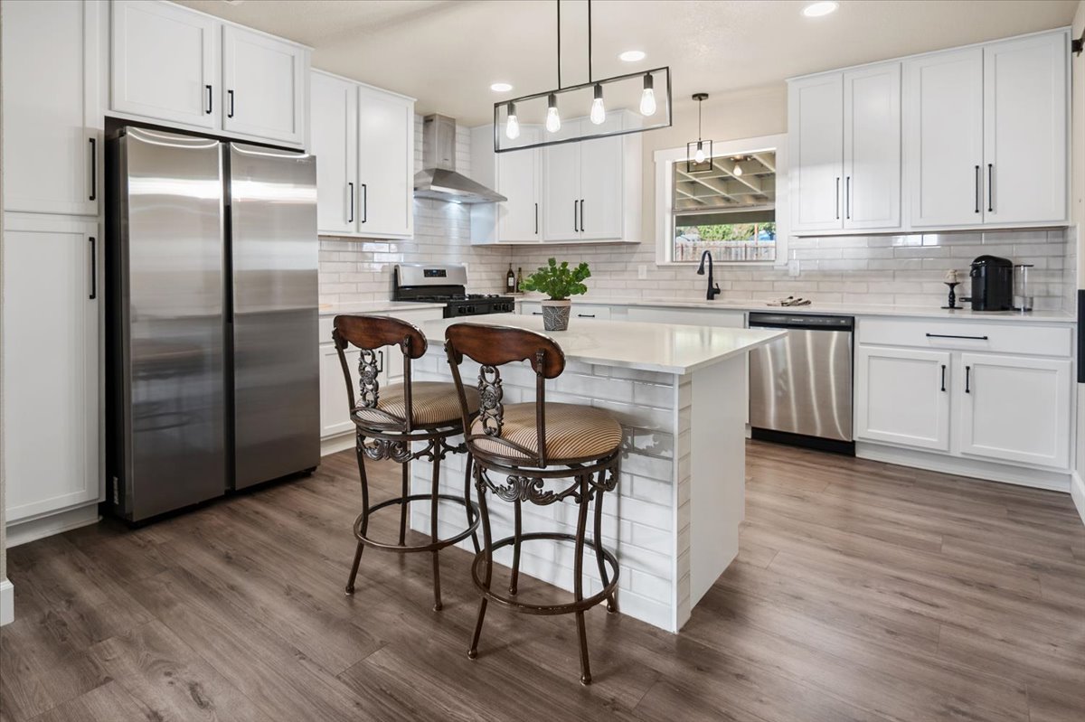 1236 Martin Street Mason, TX 76856 - Photo 8 of 40 a kitchen with stainless steel appliances granite countertop a white refrigerator a sink a stove a dining table and chairs with wooden floor