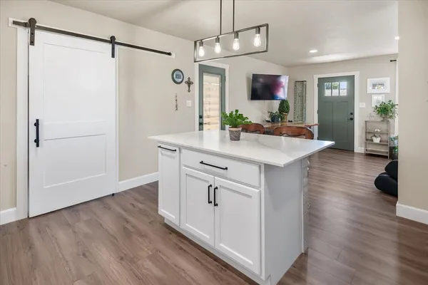 a kitchen with kitchen island white cabinets and wooden floor