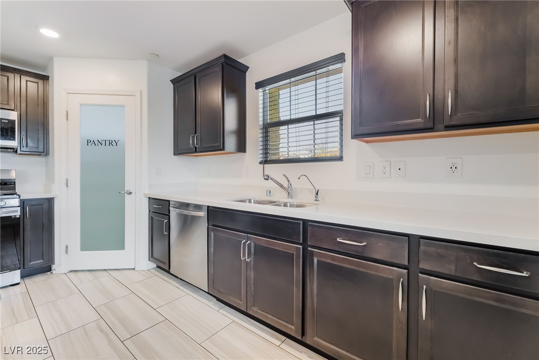 715 Pickled Pepper Place Henderson, NV 89011 - Photo 12 of 31 Kitchen with stainless steel appliances, dark brown cabinetry, recessed lighting, and light tile patterned floors