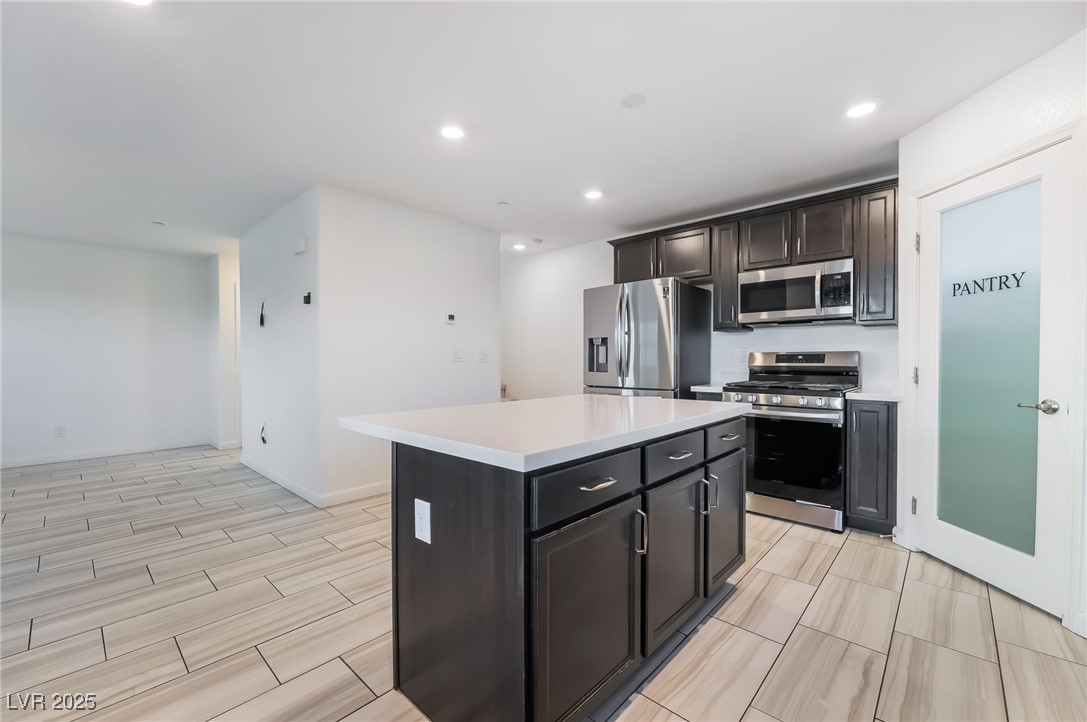 715 Pickled Pepper Place Henderson, NV 89011 - Photo 13 of 31 Kitchen with stainless steel appliances, a kitchen island, recessed lighting, and wood tiled floors