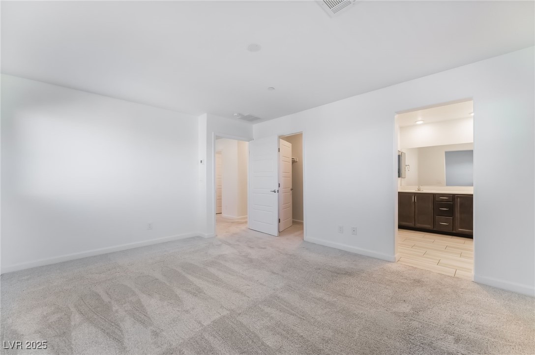 715 Pickled Pepper Place Henderson, NV 89011 - Photo 18 of 31 Unfurnished bedroom featuring a spacious closet, light carpet, and ensuite bathroom