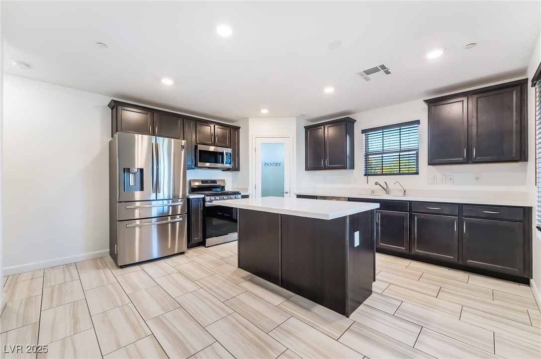 715 Pickled Pepper Place Henderson, NV 89011 - Photo 9 of 31 Kitchen featuring stainless steel appliances, dark brown cabinets, a kitchen island, recessed lighting, and wood tiled floors