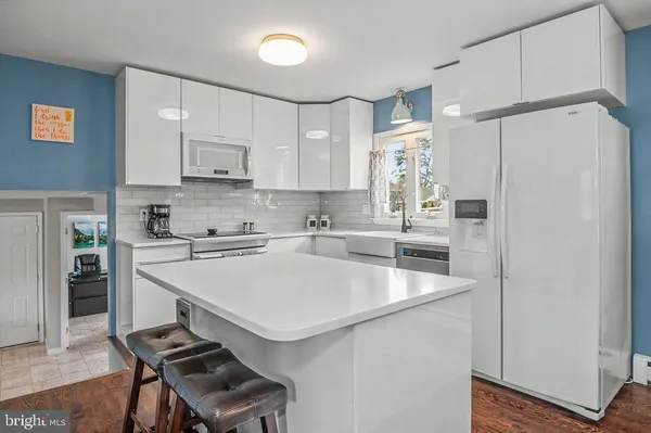 a kitchen with stainless steel appliances a refrigerator a sink and white cabinets