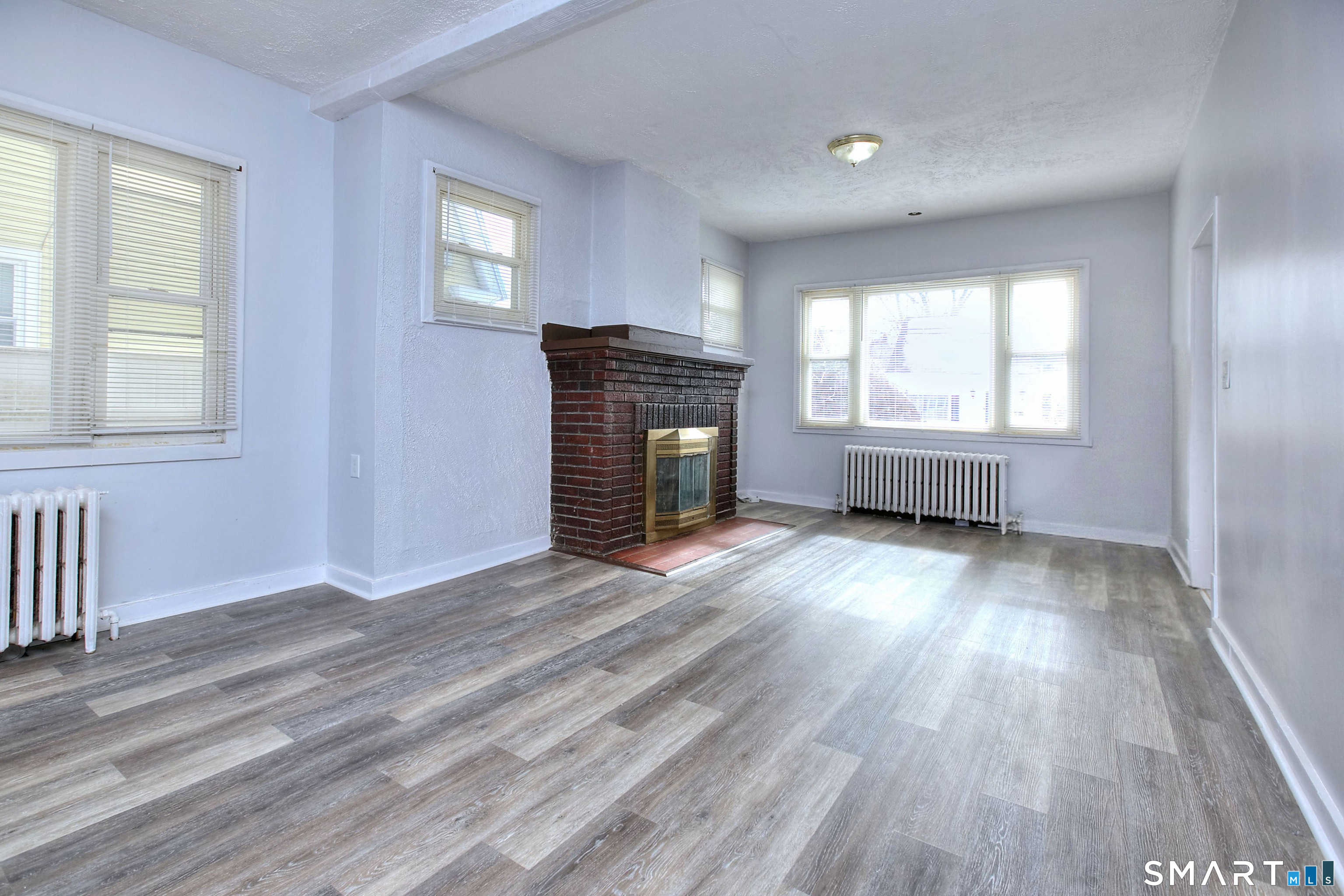 115 3rd Street Hamden, CT 06514 - Photo 8 of 34 an empty room with wooden floor fireplace and windows